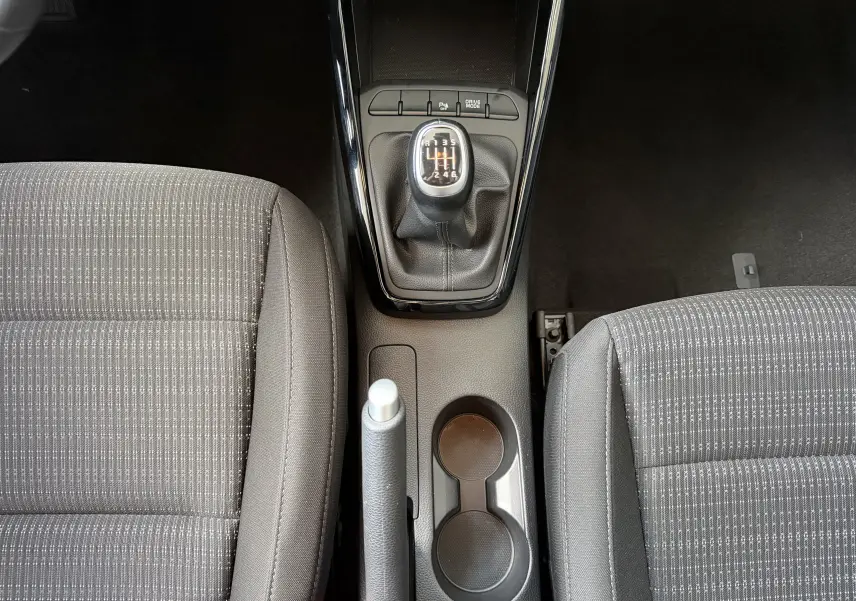 Vue intérieure centrée sur la console centrale du Kia Stonic 2023, levier de vitesse manuel et frein à main visibles.