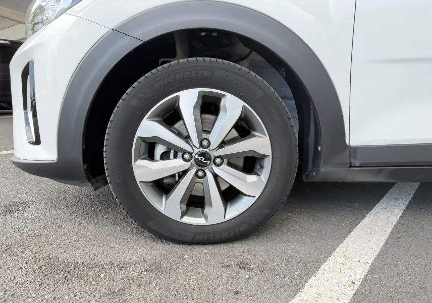 Gros plan sur la roue avant gauche d’un KIA STONIC blanc, mettant en valeur la jante alliage 16 pouces et le pneu Michelin.