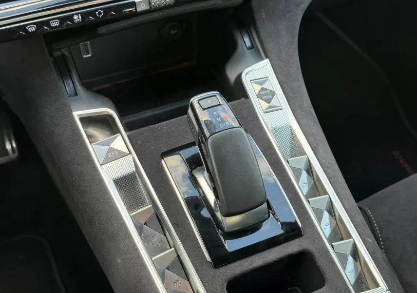 Gros plan sur la console centrale du DS7 E-TENSE 2024, avec levier de vitesse et boutons argentés sur fond noir Alcantara.