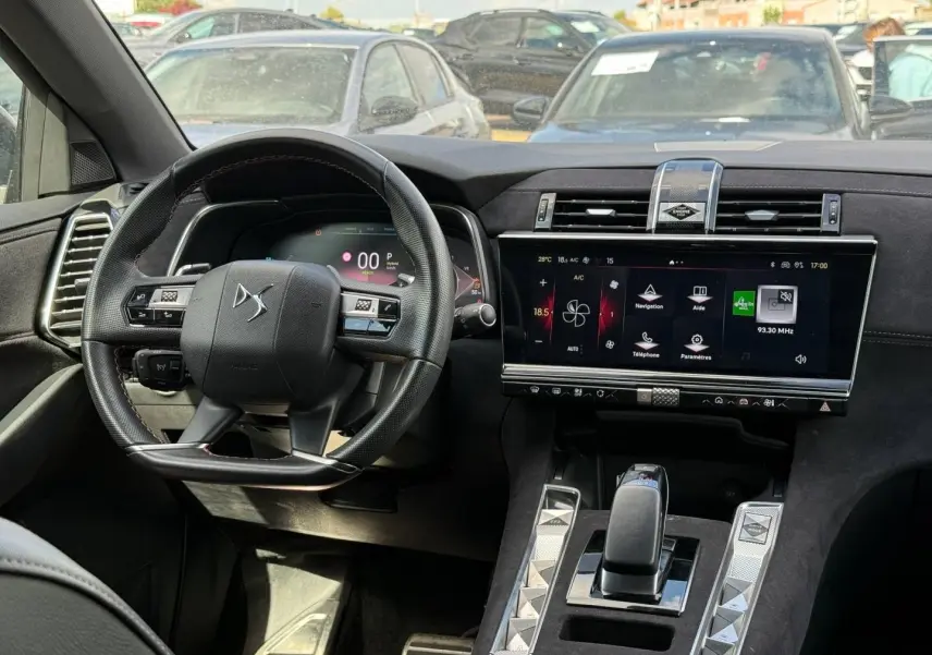 Intérieur du DS7 E-TENSE 2024 vu de face, volant cuir noir et grand écran tactile central allumé.