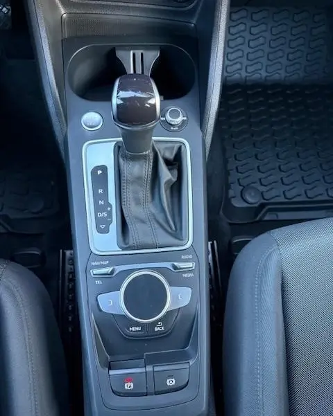 Vue plongeante sur la console centrale noire de l'Audi Q2 35 TFSI S Line 2023 avec levier de vitesses automatique et molette de commande.