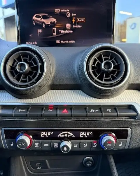 Vue rapprochée du tableau de bord noir de l'Audi Q2 35 TFSI 150 S Line 2023 avec écran tactile et commandes climatisation.