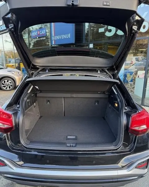 Coffre ouvert d’un Audi Q2 noir 2023 vu de l’arrière, montrant l’espace de chargement et la tablette de séparation.