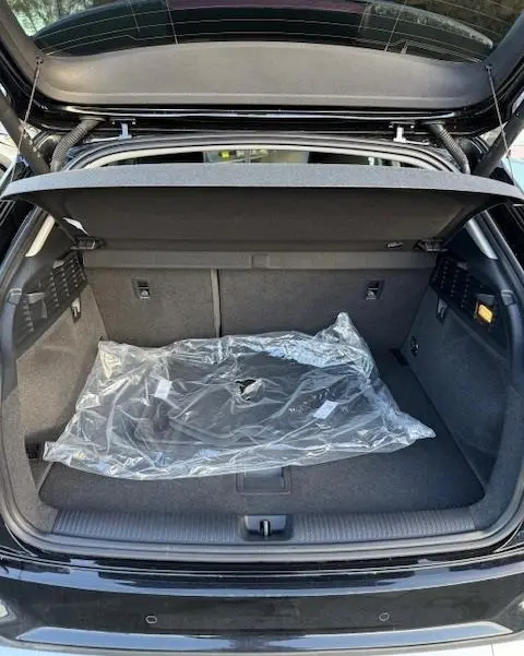 Coffre ouvert d'un Audi Q2 noir 2023, vue arrière, montrant l'espace de chargement avec tapis protégé en plastique.