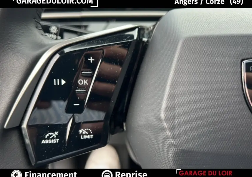 Gros plan sur les commandes au volant noir brillant du Peugeot 5008 bleu hybride 2024, avec boutons d'assistance et limitation.