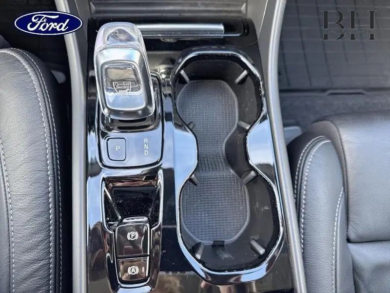 Gros plan sur la console centrale noire brillante avec levier de vitesses et porte-gobelets d’un Volvo XC40 Bleu Denim.