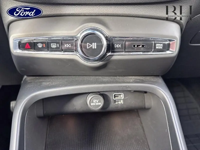 Vue rapprochée du panneau de commandes multimédia et prise 12V avec ports USB, intérieur noir d'un Volvo XC40 Bleu Denim.