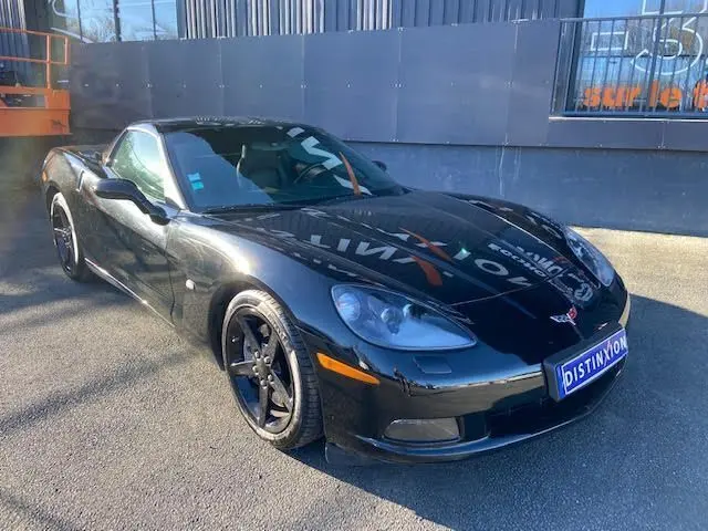 Chevrolet Corvette C6 Targa noire vue 3/4 avant droit, avec jantes noires et toit amovible visible.