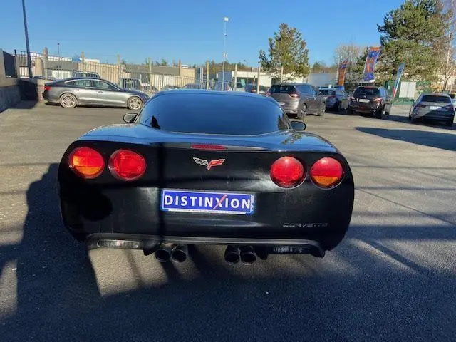 Vue arrière d'une Chevrolet Corvette C6 Targa noire de 2005 avec feux ronds et double sortie d'échappement centrale.