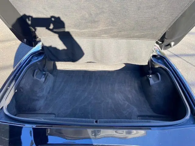Coffre ouvert d'une Chevrolet Corvette C6 Targa noire de 2005, montrant un espace de rangement propre et vide.
