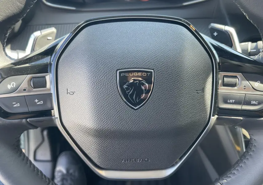 Gros plan sur le volant compact cuir noir avec logo Peugeot Lion chromé du 208 New II 2024 noir Onyx