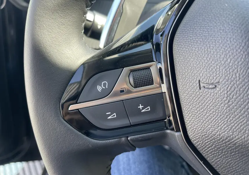 Gros plan sur les commandes vocales et volume du volant cuir noir du Peugeot 208 New II 2024.