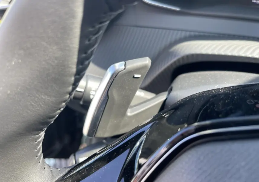 Gros plan sur la palette de changement de vitesse côté gauche du volant cuir noir du Peugeot 208 Noir Onyx 2024.