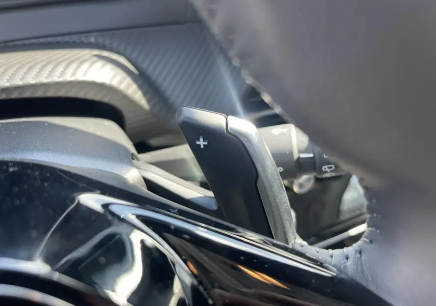 Gros plan sur la palette de changement de vitesse + côté droit du volant cuir du Peugeot 208 noir Onyx 2024.