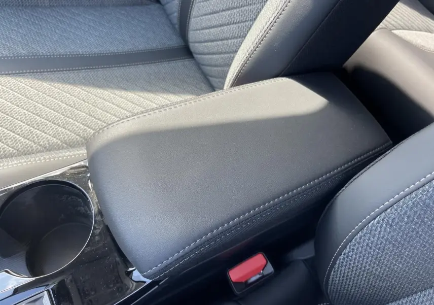 Gros plan sur l'accoudoir central noir et la sellerie tissu gris du PEUGEOT 208 NEW II 2024 côté console centrale.