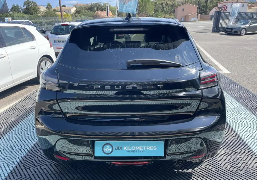 Vue arrière d'une Peugeot 208 noire Onyx 2024 avec feux LED 3 griffes et logo Peugeot lumineux sur le hayon.