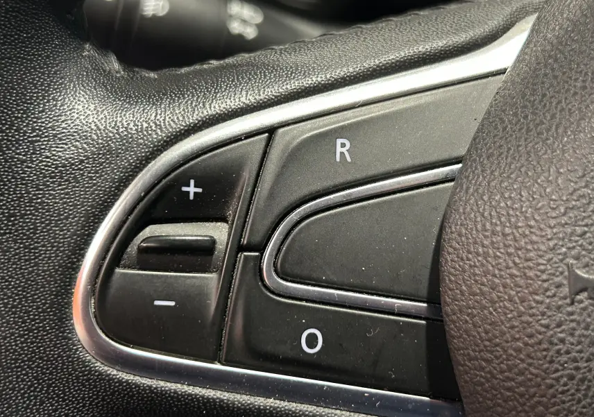 Gros plan sur les commandes de régulateur de vitesse au volant en cuir noir du Renault Kadjar gris de 2015.