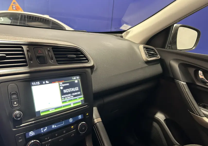Intérieur du Renault Kadjar 2015 côté passager, tableau de bord noir avec écran tactile et commandes de climatisation.