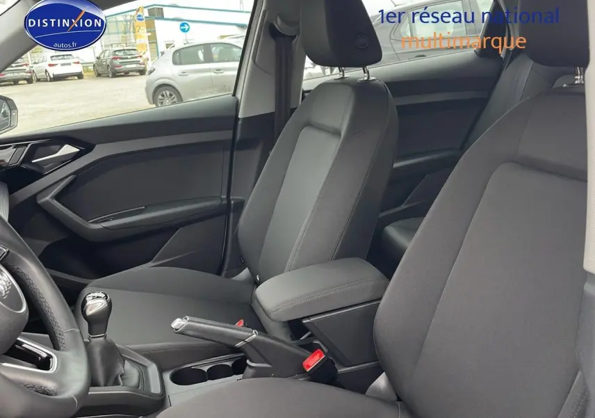 Vue intérieure de l'Audi A1 Sportback 30 TFSI 2022 montrant les sièges avant gris et l'accoudoir central.