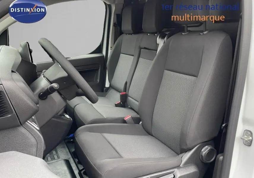 Vue intérieure côté conducteur du Peugeot Expert Fourgon blanc 2025, montrant les sièges avant en tissu gris et le volant.