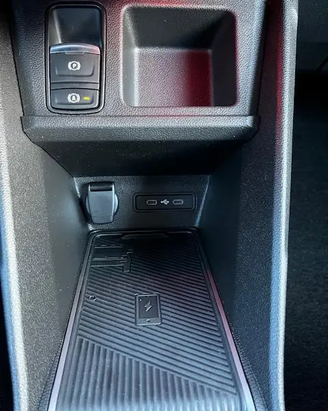 Gros plan sur la console centrale noire de la Renault R5 Techno électrique 2024, avec chargeur sans fil et prises USB.