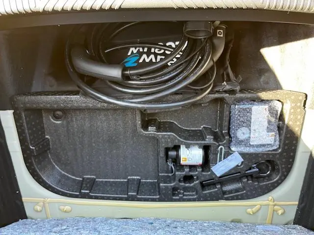 Vue rapprochée du coffre arrière ouvert de la Renault R5 Techno jaune 2024, montrant le rangement avec câble de charge et outils.