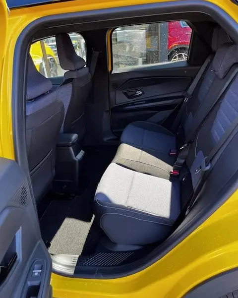 Vue intérieure arrière côté gauche d'une Renault R5 jaune 2024, montrant les sièges arrière en tissu gris et noir.