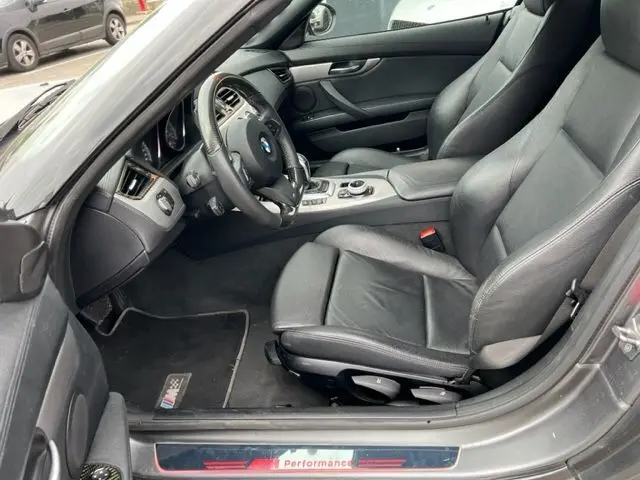 Intérieur côté conducteur du BMW Z4 Roadster gris 2012, sièges cuir noirs et seuil de porte M Performance visible.
