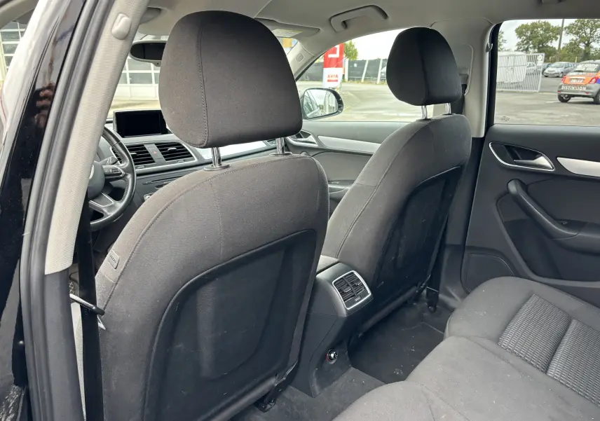 Vue arrière intérieure du Audi Q3 noir 2014 montrant les sièges avant et la banquette arrière en tissu noir.