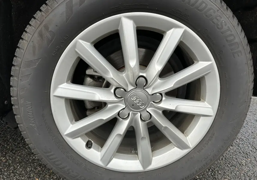 Gros plan sur la jante argentée à dix branches avec logo Audi au centre du Q3 noir de 2014.