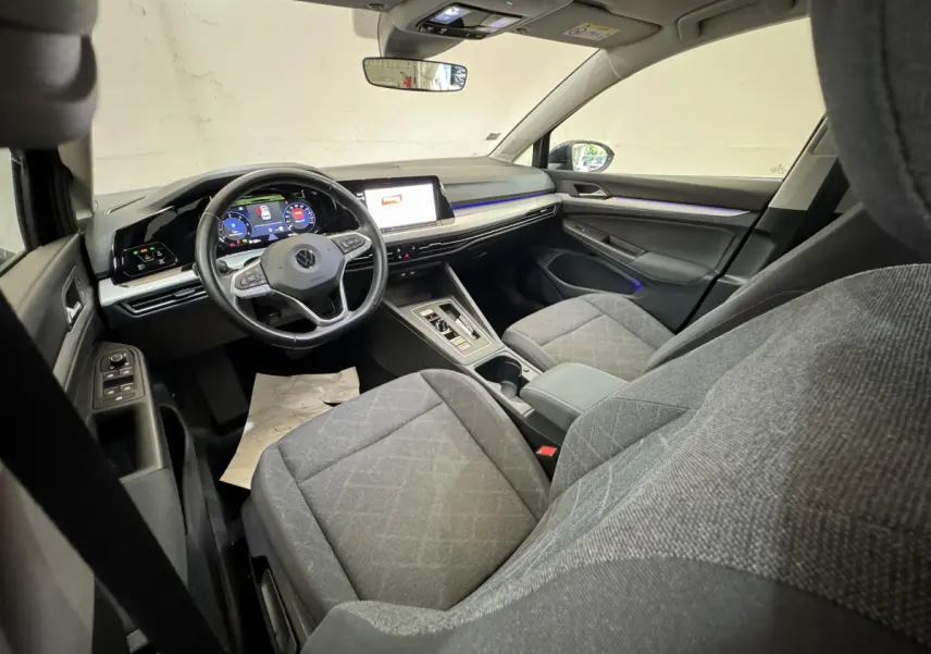 Vue intérieure avant droite de la Volkswagen Golf 2.0 TDI 2021, sièges gris et tableau de bord digital avec écran tactile.