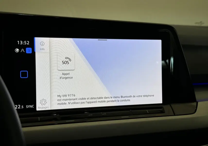 Écran tactile central affichant l'appel d'urgence dans l'habitacle d'une Volkswagen Golf bleu 2021.