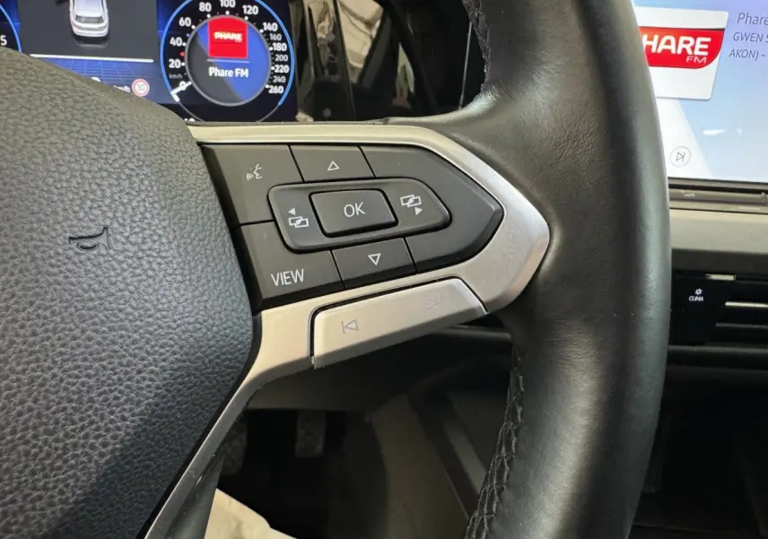 Gros plan sur le volant cuir noir de la Volkswagen Golf 2.0 TDI 2021 avec commandes multifonctions et tableau de bord digital.