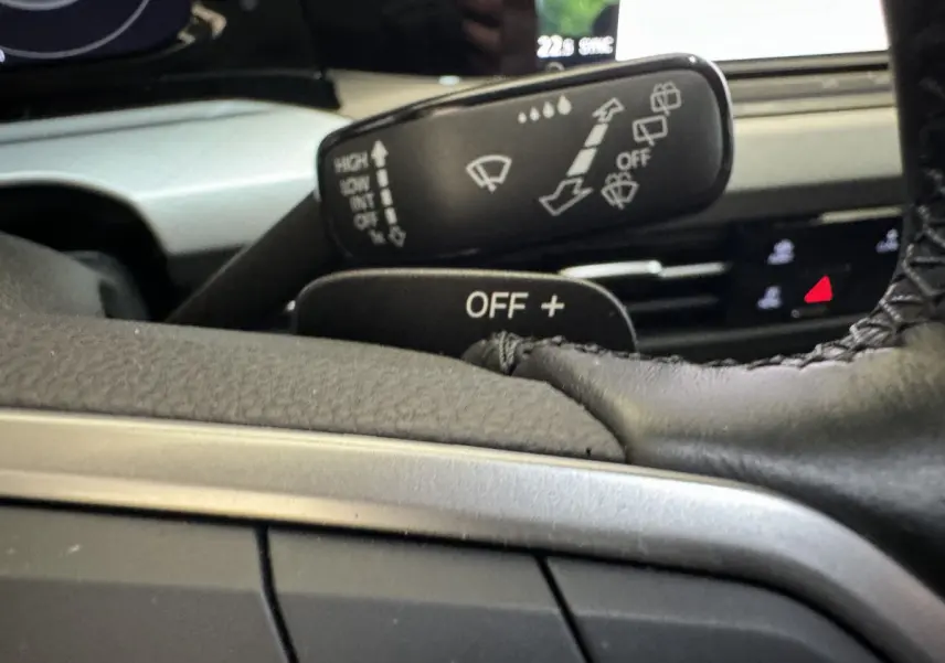 Gros plan sur la manette d'essuie-glace et le volant cuir de la Volkswagen Golf bleu, tableau de bord en arrière-plan flou.