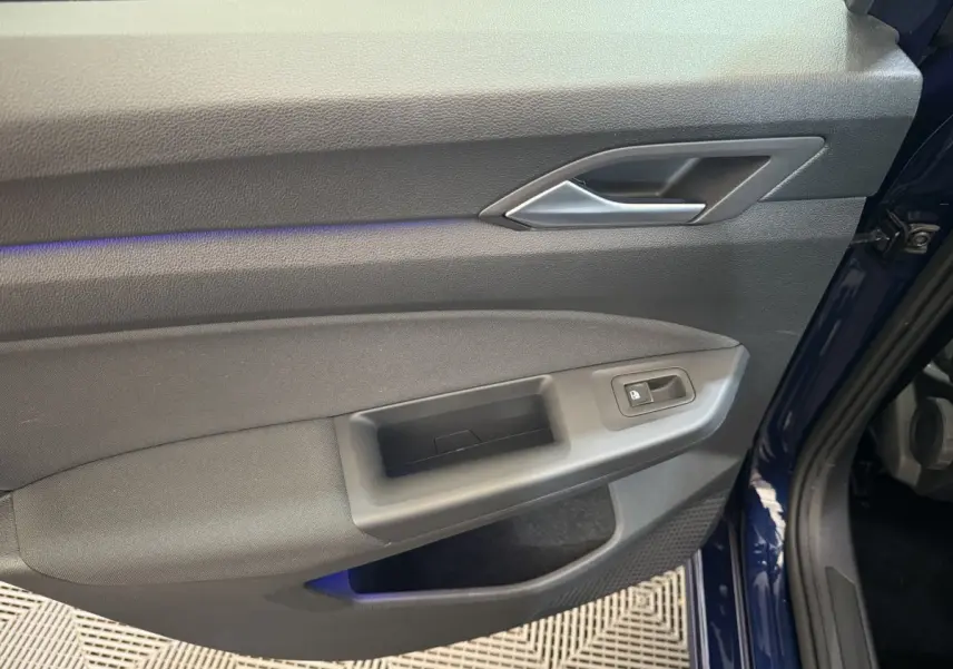 Intérieur côté gauche de la porte avant d'une Volkswagen Golf bleu 2021, avec bouton verrouillage et poignée grise.