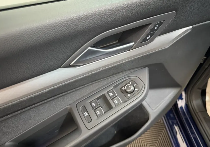 Gros plan sur la porte côté conducteur d’une Volkswagen Golf bleu 2021, avec commandes électriques et verrouillage.