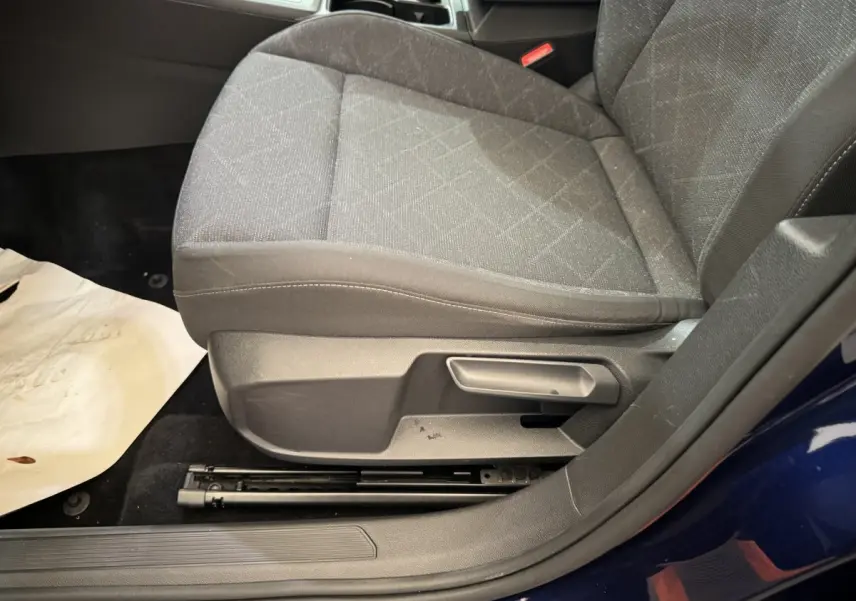 Gros plan sur le siège avant gauche tissu gris d'une Volkswagen Golf bleu 2021, avec réglage manuel visible.