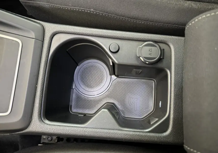 Gros plan sur la console centrale noire de la Volkswagen Golf bleu, montrant un espace de recharge sans fil et une prise 12V.