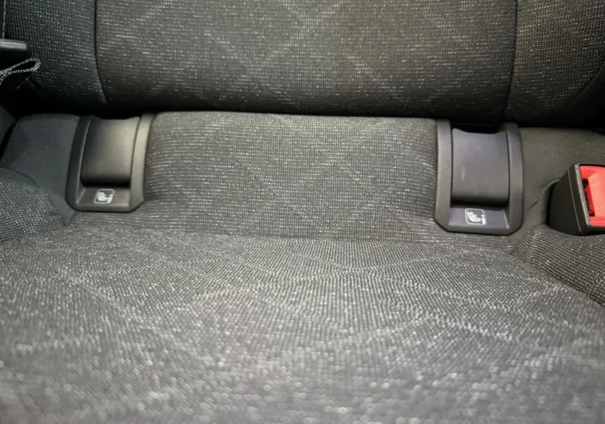 Gros plan sur l’assise arrière en tissu gris foncé avec fixations ISOFIX et boucle de ceinture rouge visible.