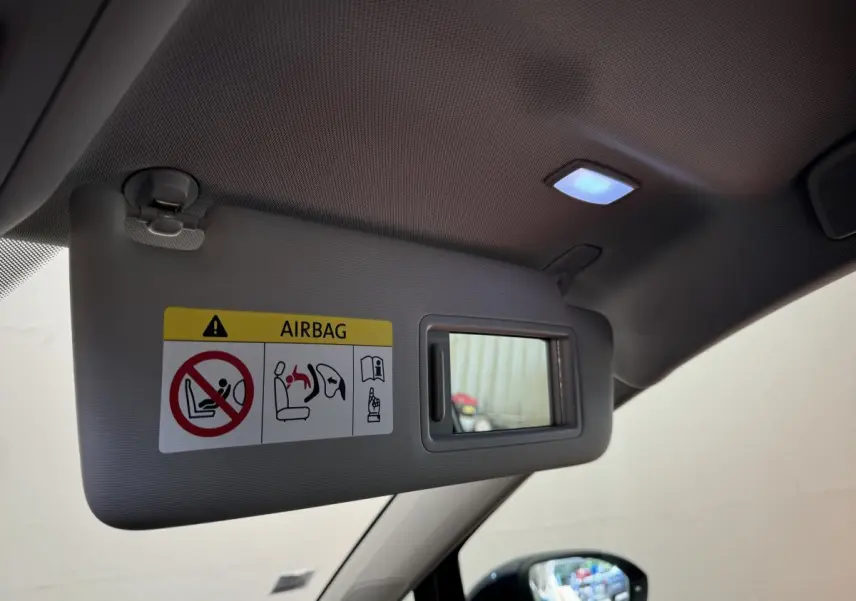 Détail du pare-soleil côté conducteur avec miroir et avertissement airbag dans une Volkswagen Golf bleu 2021.