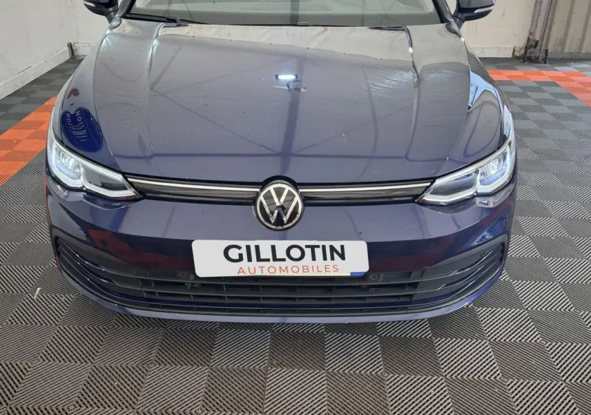 Vue avant rapprochée d'une Volkswagen Golf bleu foncé avec calandre noire et logo VW centré.