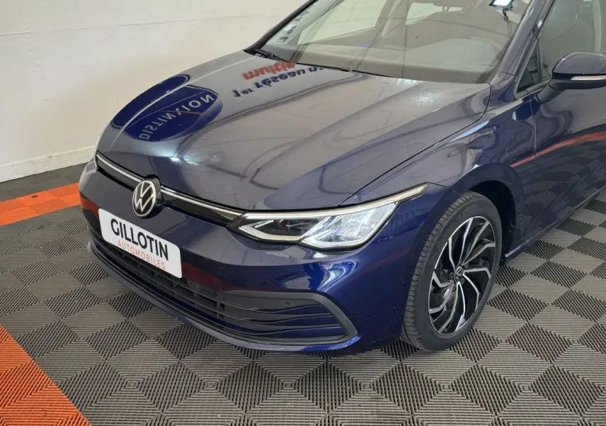 Vue 3/4 avant droit d'une Volkswagen Golf bleu profond avec phares LED et jantes alliage distinctives.