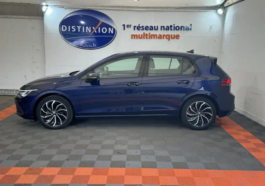 Profil côté gauche d'une Volkswagen Golf bleu foncé 2021, avec jantes alliage au design moderne, en intérieur showroom.