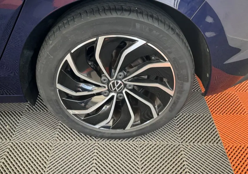 Gros plan sur la roue avant droite d'une Volkswagen Golf bleu 2021 avec jante alliage noire et argentée design moderne.