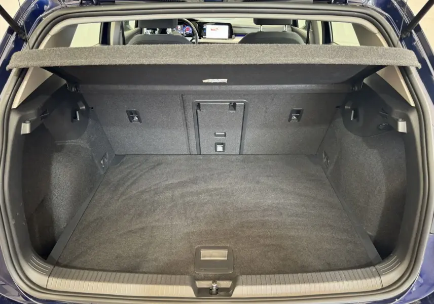 Coffre ouvert d'une Volkswagen Golf bleu 2021, vue de l'arrière avec tablette cache-bagages et intérieur noir.