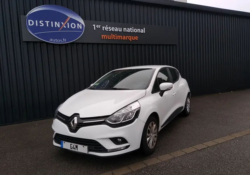 Renault Clio IV Société blanche vue 3/4 avant droit, garée devant un mur noir avec enseigne Distinxion.