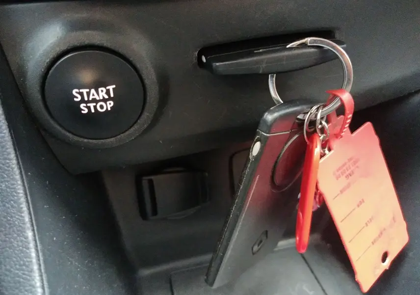 Gros plan sur la clé de contact insérée dans une Renault Clio IV Société blanche, avec bouton Start Stop visible.