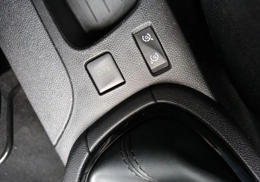 Gros plan sur les commandes ECO et régulateur de vitesse près du levier de vitesses d'une Renault Clio IV Société blanche.