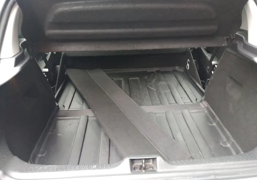 Coffre ouvert d'une Renault Clio IV Société blanche, montrant le plancher en plastique et une séparation amovible noire.