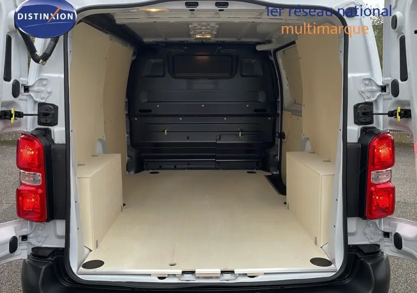 Vue arrière du Peugeot Expert Fourgon blanc 2025 avec portes ouvertes, montrant l'espace de chargement aménagé en bois clair.